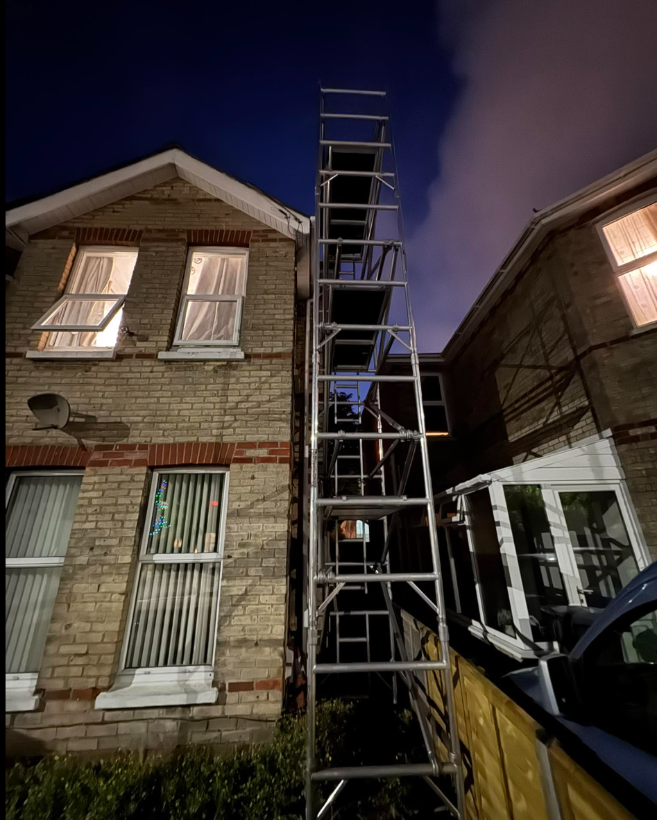 Scaffolding tower beside residential property at night