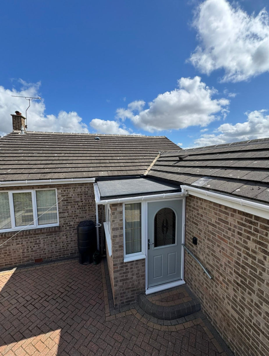 Completed roofing project on brick house with extension